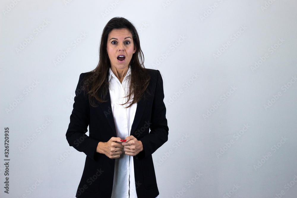 Portrait of caucasian bussiness woman model with stunned expression, keeps mouth opened, isolated on gray background studio shot, white shirt and black jacket. Place for your text in copy space. Portrait of caucasian bussiness woman model with stunned expression, keeps mouth opened, isolated on gray background studio shot, white shirt and black jacket. Place for your text in copy space.