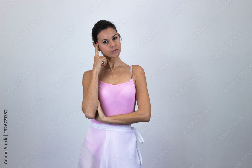 Portrait of thoughtful ballet dancer, middle age woman thinks with finger on head, isolated on gray background studio shot, ballet jersey, dark air. Place for your text in copy space. Portrait of thoughtful ballet dancer, middle age woman thinks with finger on head, isolated on gray background studio shot, ballet jersey, dark air. Place for your text in copy space.