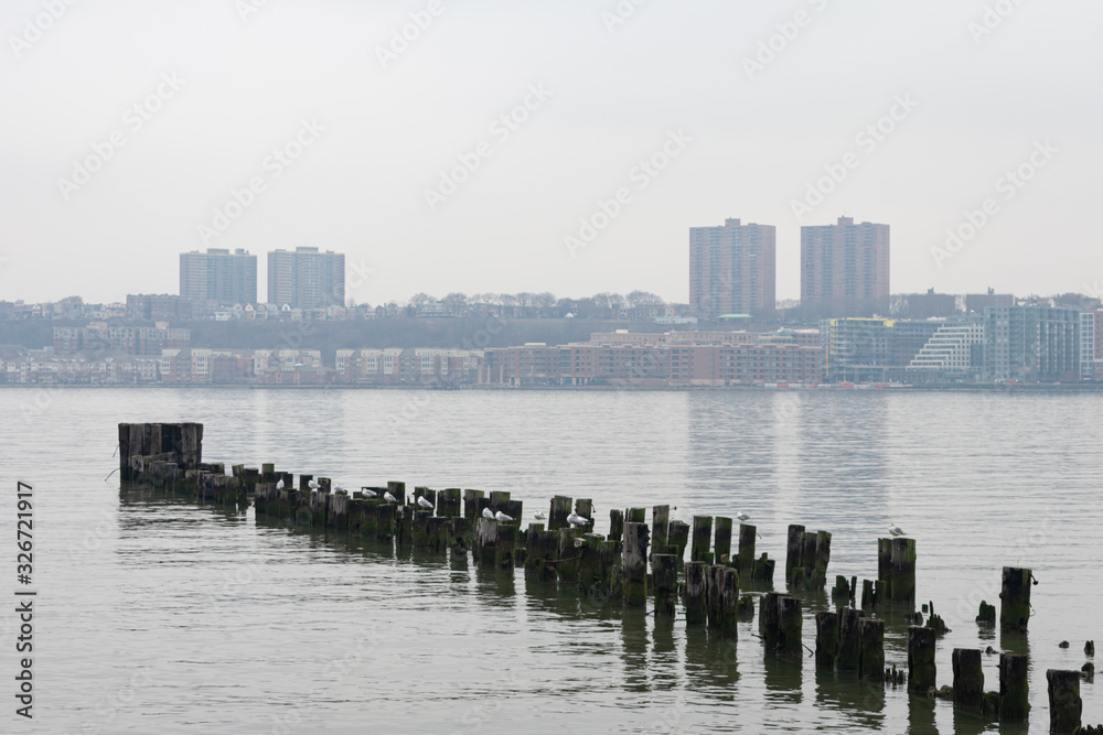 Wood Posts in the Hudson River along the Shore of Lincoln Square New York City with a view of West New York New Jersey during a Foggy Day