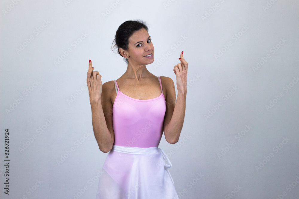 Portrait of ballet dancer, middle age woman model keeping finger crossed, having calm expression, isolated on gray background studio shot, ballet jersey, dark air. Place for your text in copy space. Portrait of ballet dancer, middle age woman model keeping finger crossed, having calm expression, isolated on gray background studio shot, ballet jersey, dark air. Place for your text in copy space.