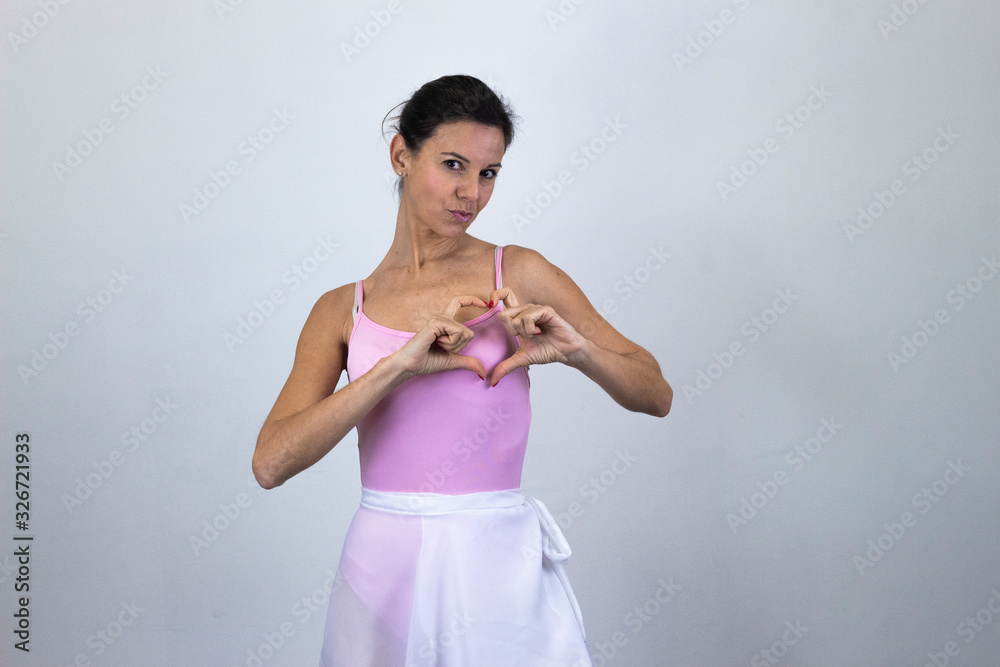 Portrait of ballet dancer, caucasian middle age woman showing shape heart with hands, expressing love, isolated on gray background studio shot, ballet jersey, dark air. Place for your text in copy spa Portrait of ballet dancer, caucasian middle age woman showing shape heart with hands, expressing love, isolated on gray background studio shot, ballet jersey, dark air. Place for your text in copy spa