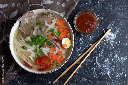 Flat lay, vietnamese food, pho bo soup on black background with sauce. photo