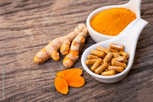 Turmeric ( curcumin, Curcuma ) powder and tumeric capsule isolated on wood background. Supplement concept. Top view. 