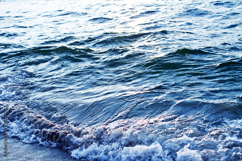 Blue wavy sea background. Sea water turbulent surface. Ocean waves. Sea shore sunligh reflection texture.