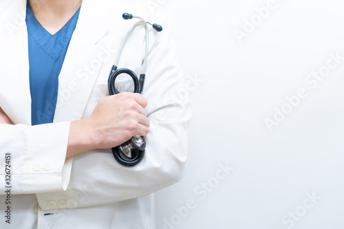 A specialist doctor in blue scrub uniform with white gown holding a stethoscope in the hospital (white background)