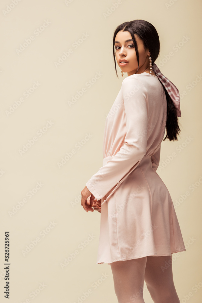 attractive african american girl in dress posing isolated on beige attractive african american girl in dress posing isolated on beige