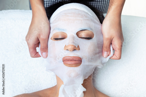 Cosmetologist making the vitamin C facial mask for rejuvenation to woman on the spa center. photo