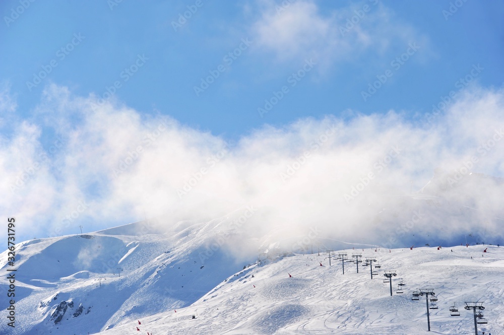 Ski resort view with chair lifts under clouds and snow 