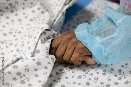 A mother's hand holding her son foot in hospital