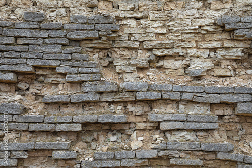 The brown and grey  cobblestone or brick tower, fortress or castle wall background or texture