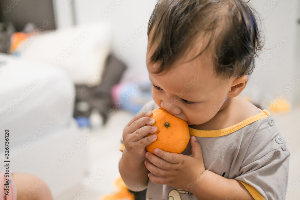 asia little baby eating orange. high angle shot. asia little baby eating orange. high angle shot.
