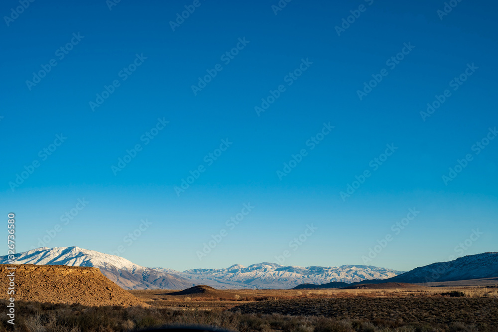 blue sky copy space above desert valley and snowy mountains wilderness landscape