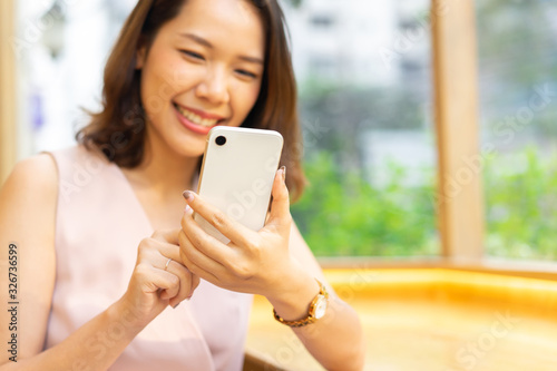 close up young beautiful asian thai woman hand holding smartphone to playing application and reading content on social media network at cafe restaurant in relaxation weekend day for city lifestyle