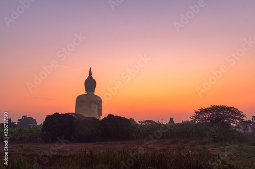 scenery sunrise in front of the great Buddha of Thailand at wat Muang Ang Thong Thailand. .The largest Buddha statue in the world Can be seen from afar Surrounded by rice fields.