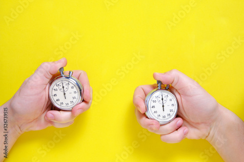 Mechanical stopwatches in two hands on a yellow background. photo