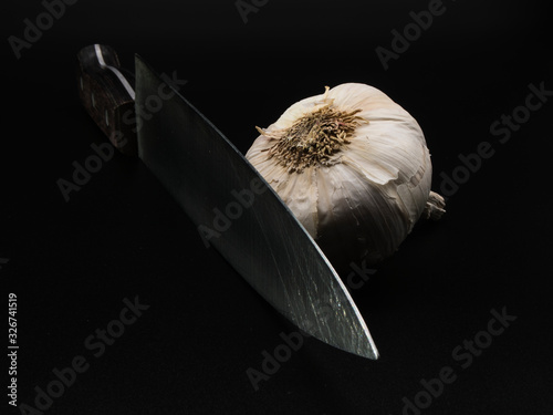 Cabeza de ajo y cuchillo de cocina en fondo negro
