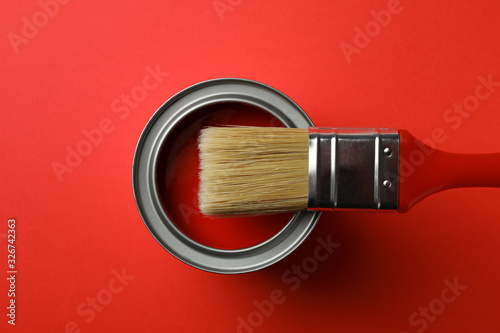 Paint can and brush on red background, top view