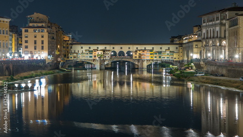 Famous Ponte Vecchio bridge timelapse over the Arno river in Florence, Italy, lit up at night © neiezhmakov