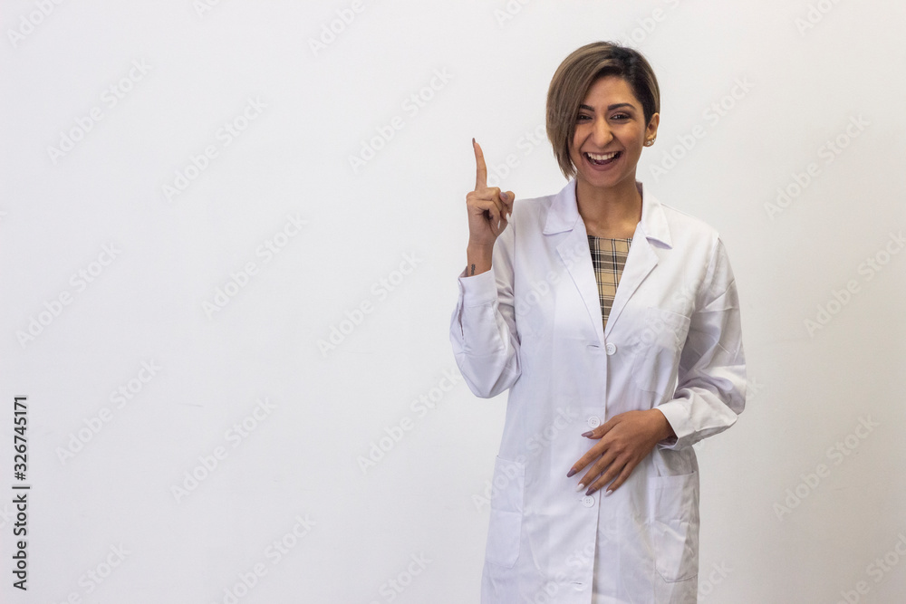 Portrait of happy latin young woman smiling pointing up aside with index finger and looking at camera, having great idea. Pharmacist, beauty therapist, doctor, nurse, scientist, ophthalmologist, isola Portrait of happy latin young woman smiling pointing up aside with index finger and looking at camera, having great idea. Pharmacist, beauty therapist, doctor, nurse, scientist, ophthalmologist, isola