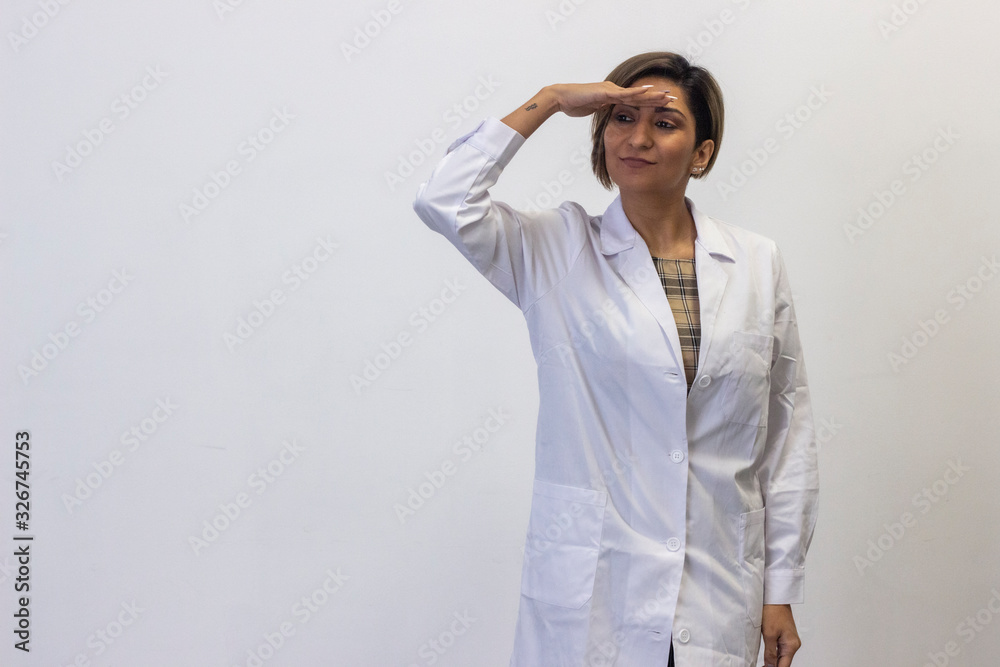 Portrait of attractive young woman peeks out someone, keeps hand near forehead. Doctor, nurse, pharmacist, scientist, therapist, teacher, isolated on white background studio shot, in white coat unifor Portrait of attractive young woman peeks out someone, keeps hand near forehead. Doctor, nurse, pharmacist, scientist, therapist, teacher, isolated on white background studio shot, in white coat unifor