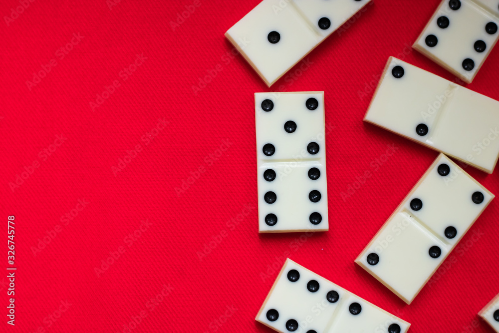Dominoes Domino bones lie on the right half against a red fabric background and plenty of room for text. Close-up Dominoes Domino bones lie on the right half against a red fabric background and plenty of room for text. Close-up