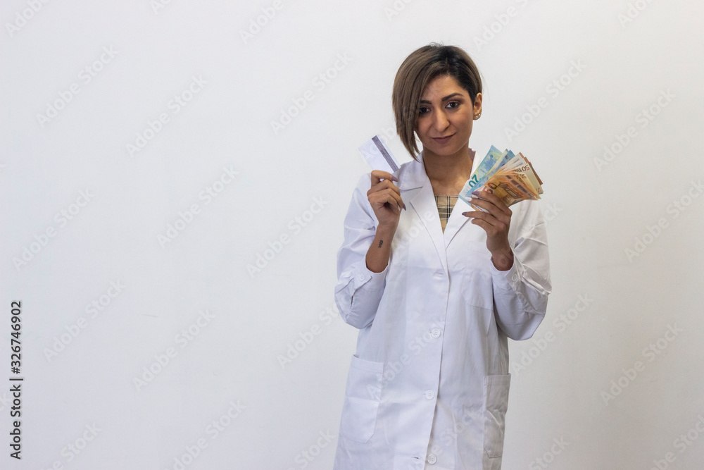 Portrait of attractive latin young woman with a credit card and euros in hands. Doctor, nurse, pharmacist, beauty therapist, scientist, ophthalmologist, optometrist, beautician, healthcare, isolated o Portrait of attractive latin young woman with a credit card and euros in hands. Doctor, nurse, pharmacist, beauty therapist, scientist, ophthalmologist, optometrist, beautician, healthcare, isolated o