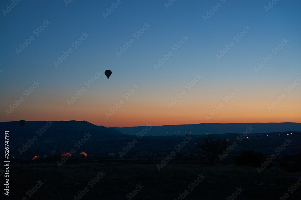 Silhouette of a flying hot air balloon in the clear sky at sunrise in Cappadocia, Central Anatolia, Turkey.
