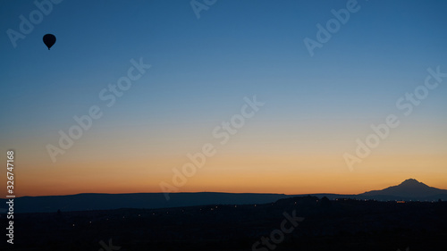 Silhouette of a flying hot air balloon in the clear sky at sunrise in Cappadocia, Central Anatolia, Turkey.