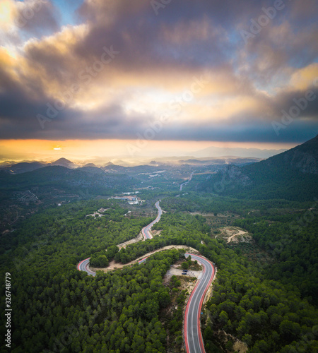 Winding road Sunrise over Alicante, Spain.  Tree covered mountains with road running through 