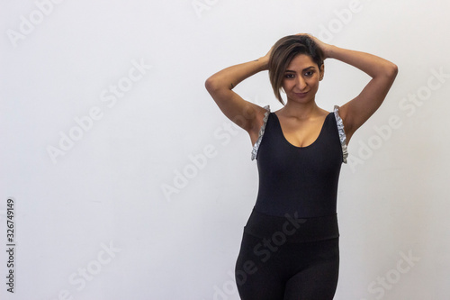 Portrait of relaxed gymnast, latin young womanwith a golf club touching his head with both hands, having time for rest, looks quiet and peaceful, isolated on white background studio shot, white t-shir photo