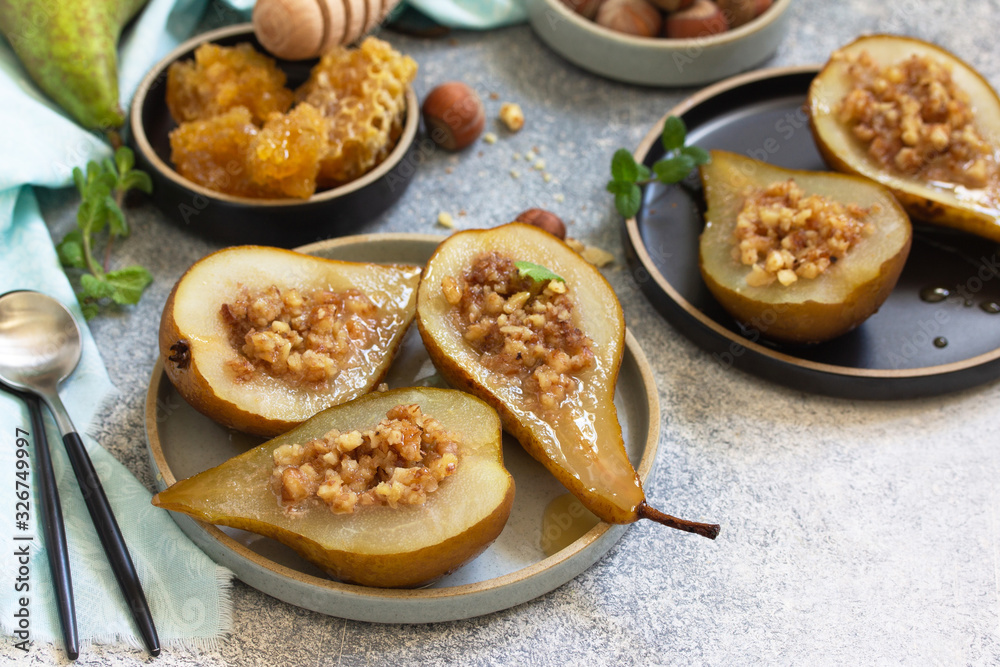 Healthy diet dessert. Baked pears with hazelnuts, honey and granola on a slate, stone or concrete background. Copy space.