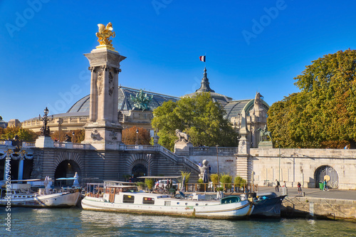 Pleasure boats docked on the Seine river next to the Alexander III Bridge, one of the most beautiful bridges that cross the Seine river, in Paris, France.