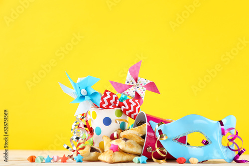 Purim holiday composition. Cookies with buckets and party supplies on yellow background