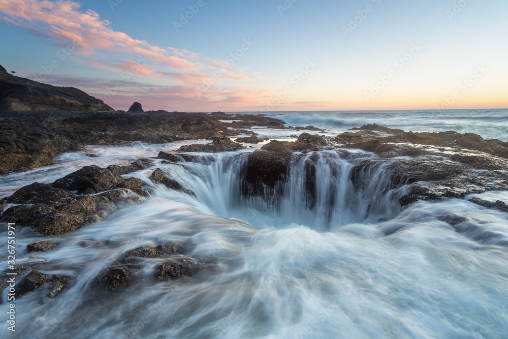 Obraz premium Thor's well Oregon Coast, waves crashing over rocks and into blowhole during a beautiful sunset