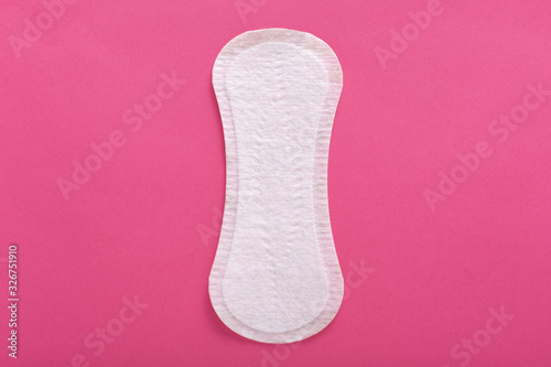 Horizontal indoor picture of clean unused unpacked sanitary pad, ready to be used, being disposable, located in middle of photo, feminine hygiene during menstruation concept. Flat lay. Top view.