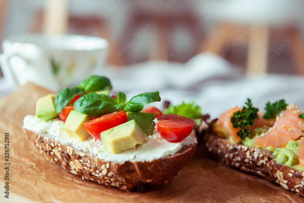 Wholegrain toast with avocado, tomato and salmon on wooden cutting board Wholegrain toast with avocado, tomato and salmon on wooden cutting board