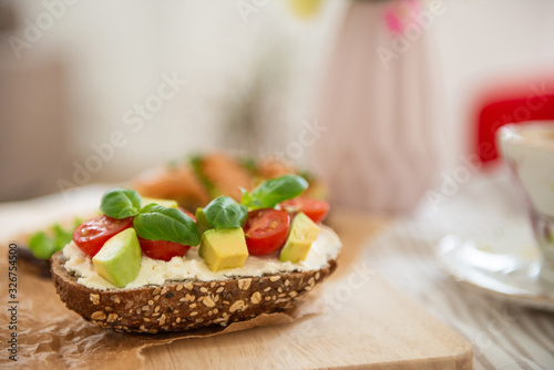 Wholegrain toast with avocado, tomato and salmon on wooden cutting board