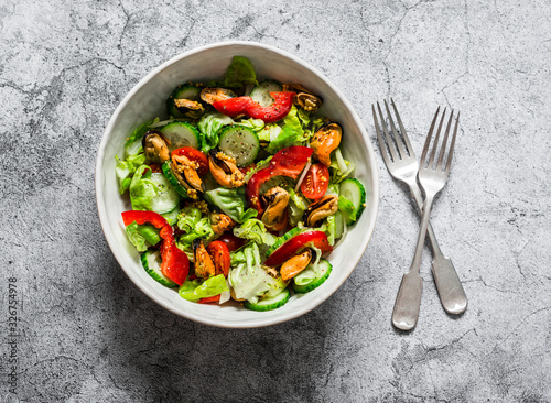 Salad with fresh vegetables and canned mussels on a gray background, top view. Delicious healthy diet food