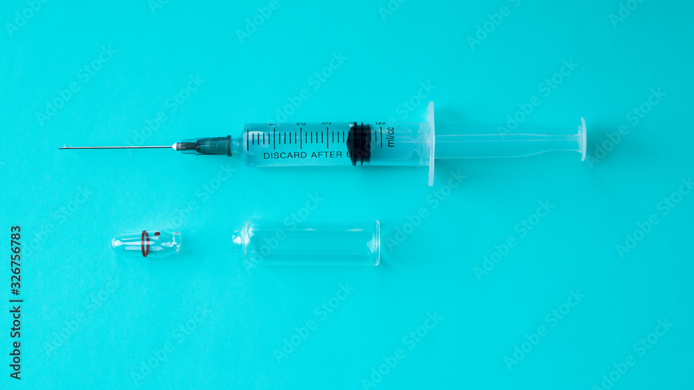 A syringe filled with medicine with an opened ampoule on a blue background. Healthcare and medicine concept. Intramuscular injection. Vaccine in an ampoule. A syringe filled with medicine with an opened ampoule on a blue background. Healthcare and medicine concept. Intramuscular injection. Vaccine in an ampoule.