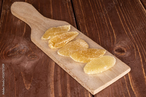 Group of five slices of dried yellow pineapple on wooden cutting board on brown wood photo