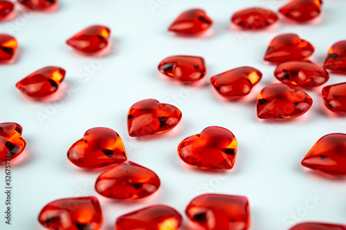 A scattering of scarlet crystal hearts on a white background.