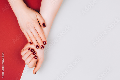 Red beautiful manicure on red and grey stylish background with copyspace. Flat lay style.