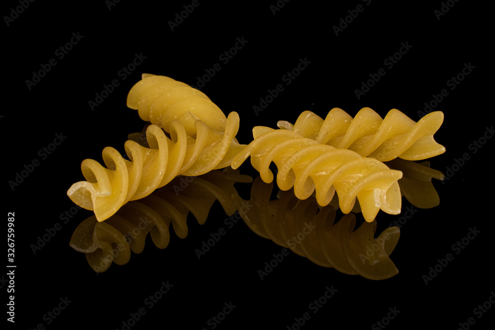 Group of four whole small yellow pasta fusilli isolated on black glass Group of four whole small yellow pasta fusilli isolated on black glass