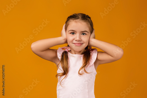 Little child girl covering her ear with her hand. I hear nothing