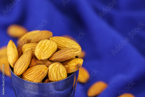 Almonds in a metal glass on a blurry blue background