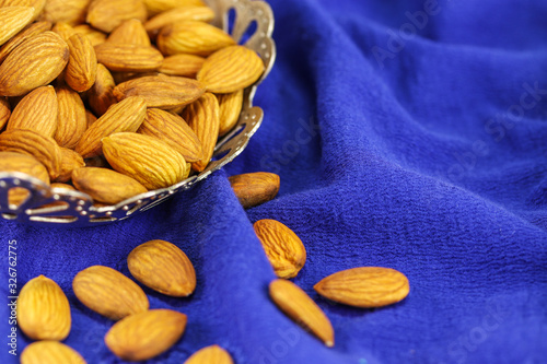 Almonds in a metal vase on a blue background