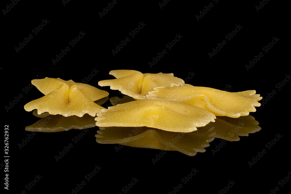 Group of four whole yellow pasta farfalle isolated on black glass Group of four whole yellow pasta farfalle isolated on black glass