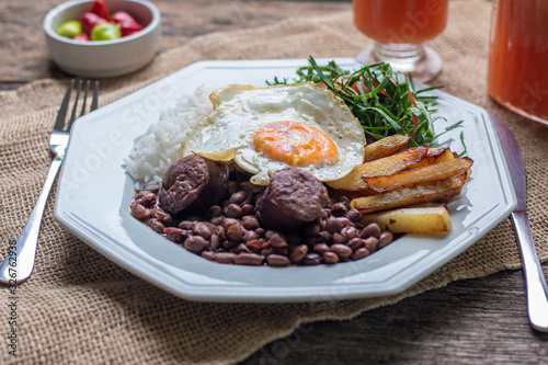 Brazilian food dish. Beans, rice, egg, salad and potatoes. Rustic wood background