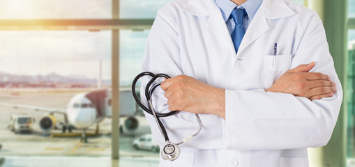 Unrecognizable male doctor standing with his arms folded inside of a airport