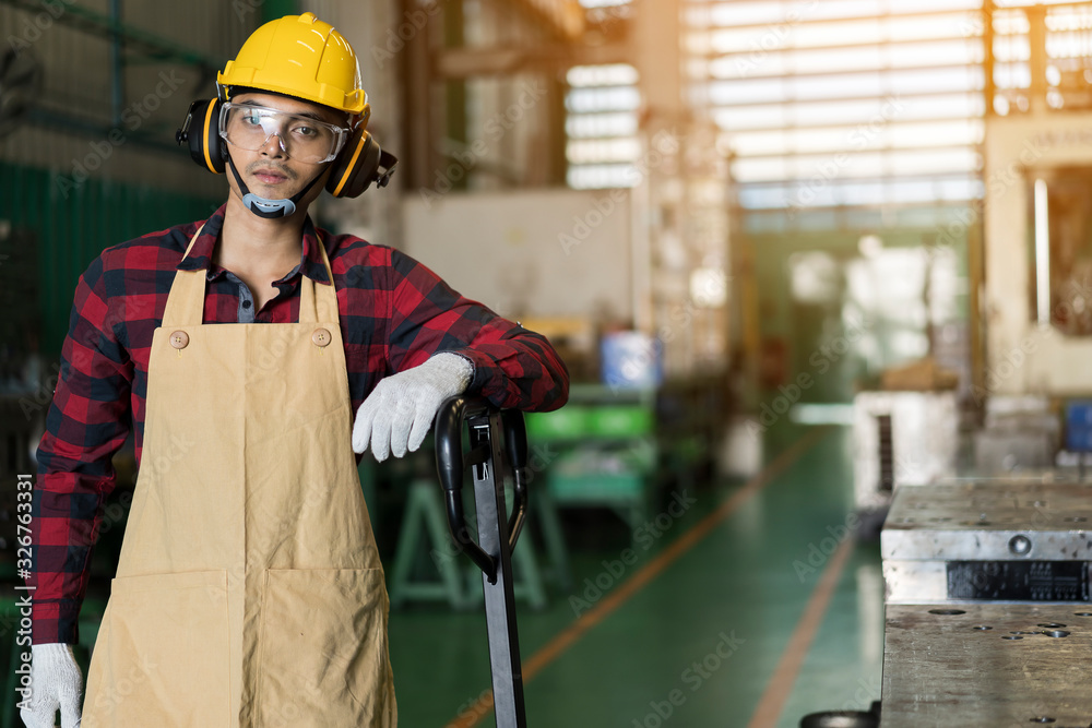 Portrait of male factory worker with safety helmet and standard safety equipment standing on interior of industrial hall, factory industry.  safety, machine in intelligent factory industrial concept